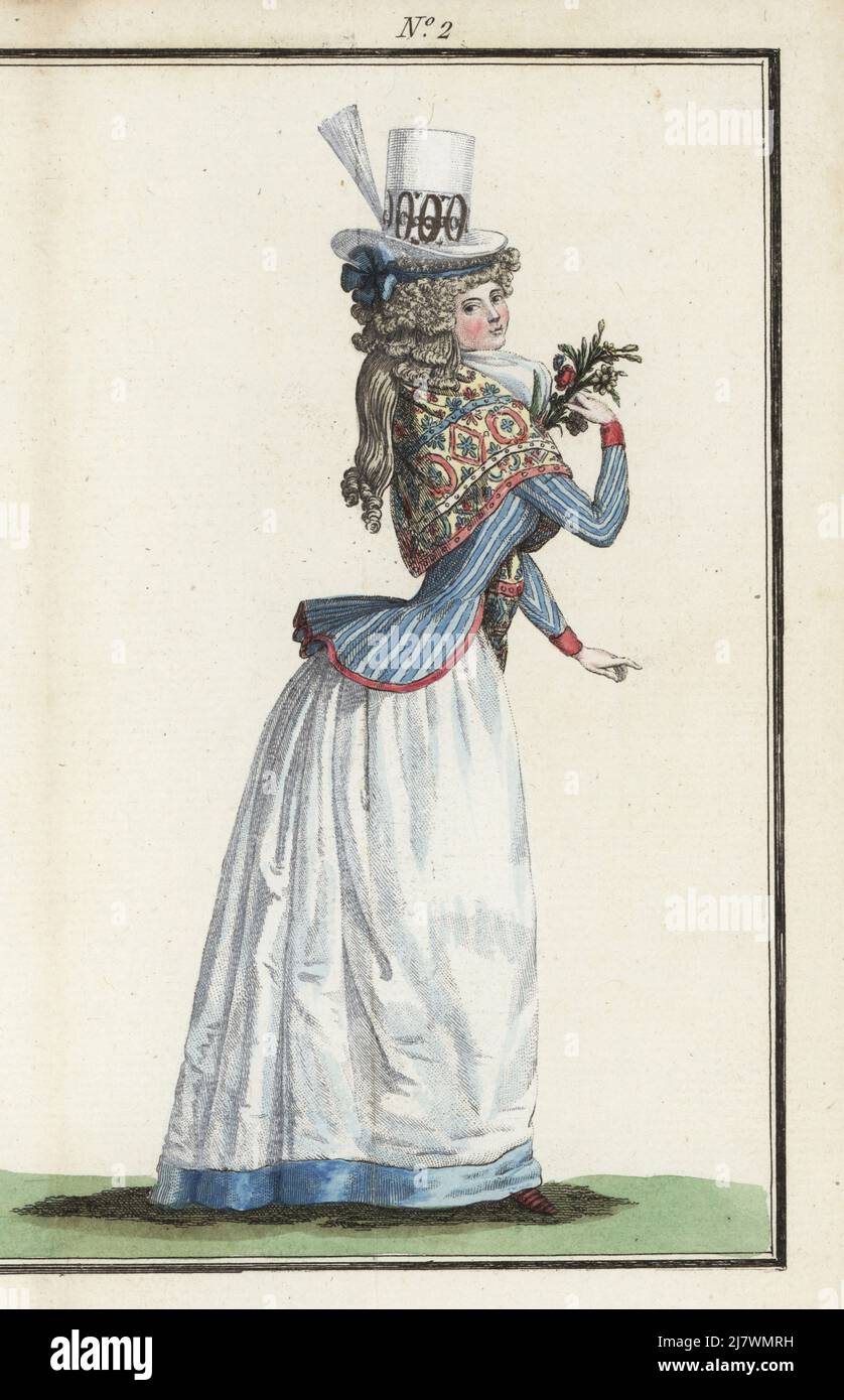 Fashionable woman in felt hat with white aigrette, embroidered kerchief or manteau, striped-blue caraco jacket, white fichu and satin skirt. Handcoloured copperplate engraving from Jean-Antoine le Brun or Lebrun-Tossa’s Journal de la Mode et du Gout, previously Cabinet des Modes, Chez Buisson, Paris, and Joseph le Boffe, London, Premier Cahier, February 1790. Stock Photo