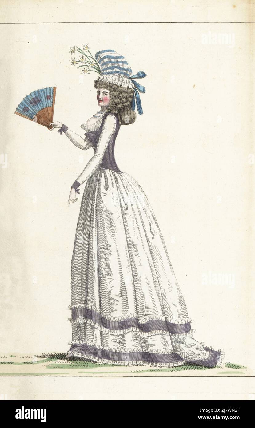 Woman in bonnet with striped taffeta top and gauze base, hairstyle with forelock and ringlets, violet taffeta fourreau, white taffeta skirt with violet bands, cameo fan. Handcoloured copperplate engraving from Jean-Antoine le Brun or Lebrun-Tossa’s Journal de la Mode et du Gout, previously Cabinet des Modes, Chez Buisson, Paris, and Joseph le Boffe, London, 13me Cahier, 25 June 1790. Stock Photo