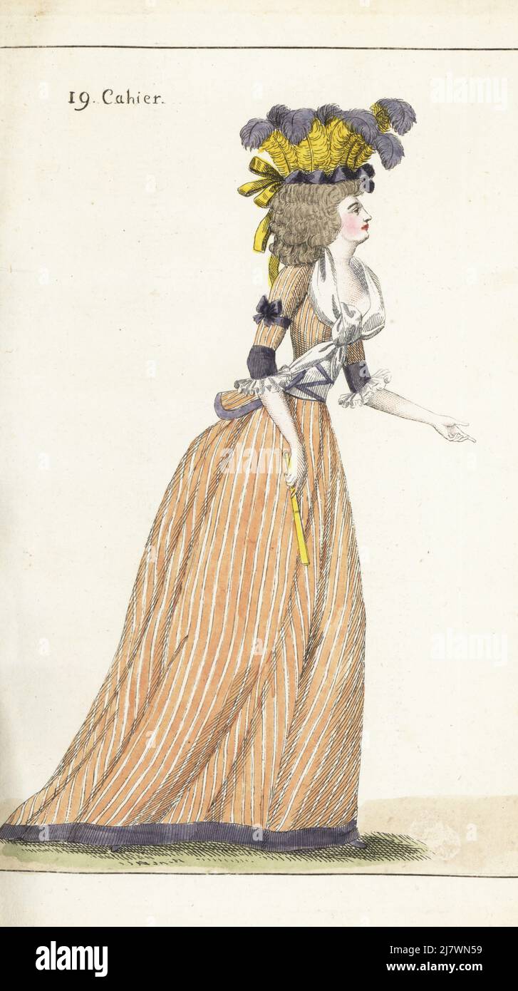 French fashionable woman or Elegant in hat of yellow and violet heron plumes, striped caraco and skirts, gauze fichu tied in front, white front with violet ribbons, yellow fan. Handcoloured copperplate engraving from Jean-Antoine le Brun or Lebrun-Tossa’s Journal de la Mode et du Gout, previously Cabinet des Modes, Chez Buisson, Paris, and Joseph le Boffe, London, 19me Cahier, 25 August 1790. Stock Photo