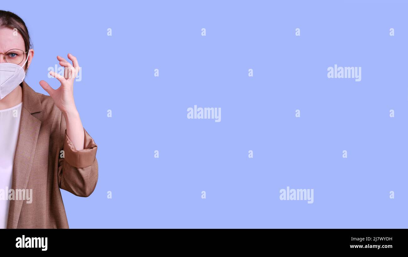 Angry woman teacher in medical face mask on studio purple background ...
