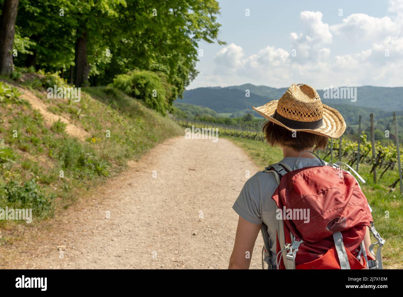 Hiking Woman with brown hair, gray t-shirt, jeans, straw hat and