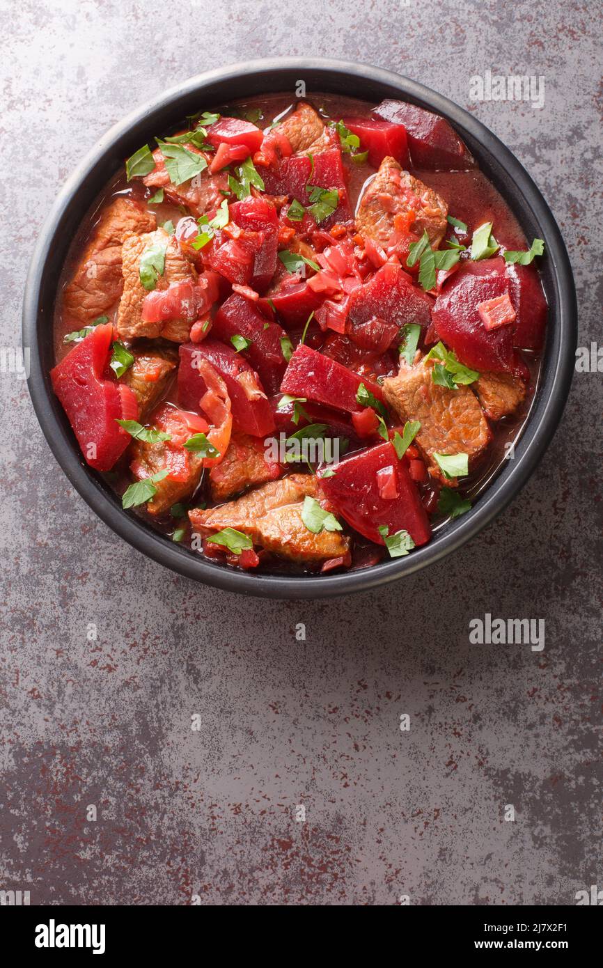 Delicious meat stew with beets and onions in a spicy sauce close-up in a bowl on the table. vertical top view from above Stock Photo