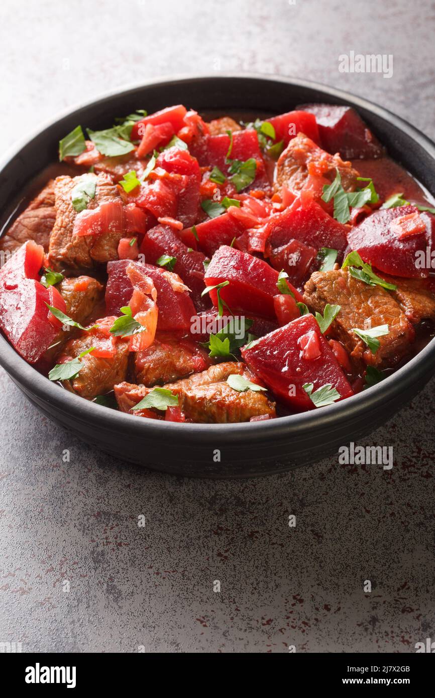 Delicious meat stew with beets and onions in a spicy sauce close-up in a bowl on the table. vertical Stock Photo