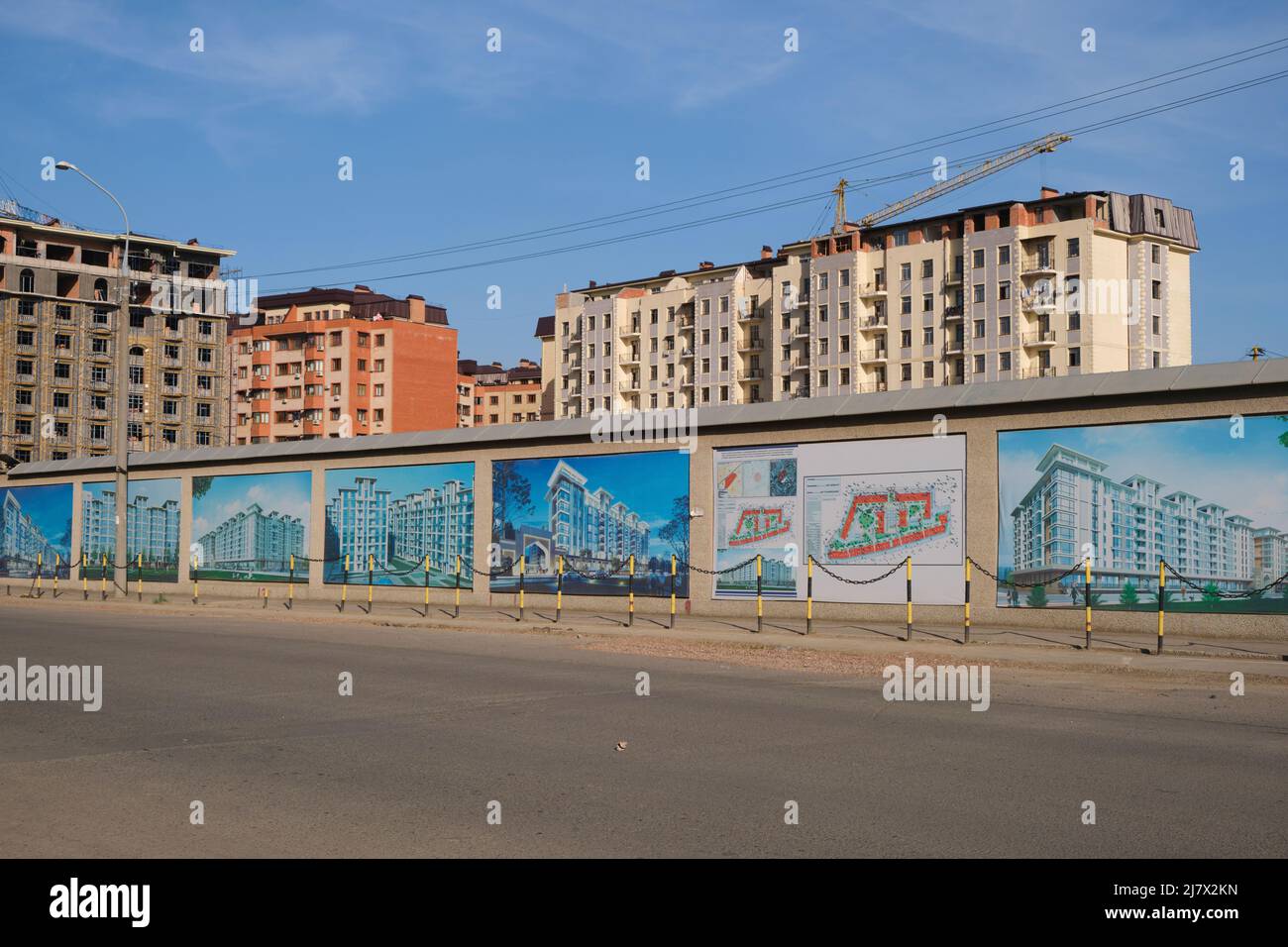 A fence with images of the new apartment development in front of a