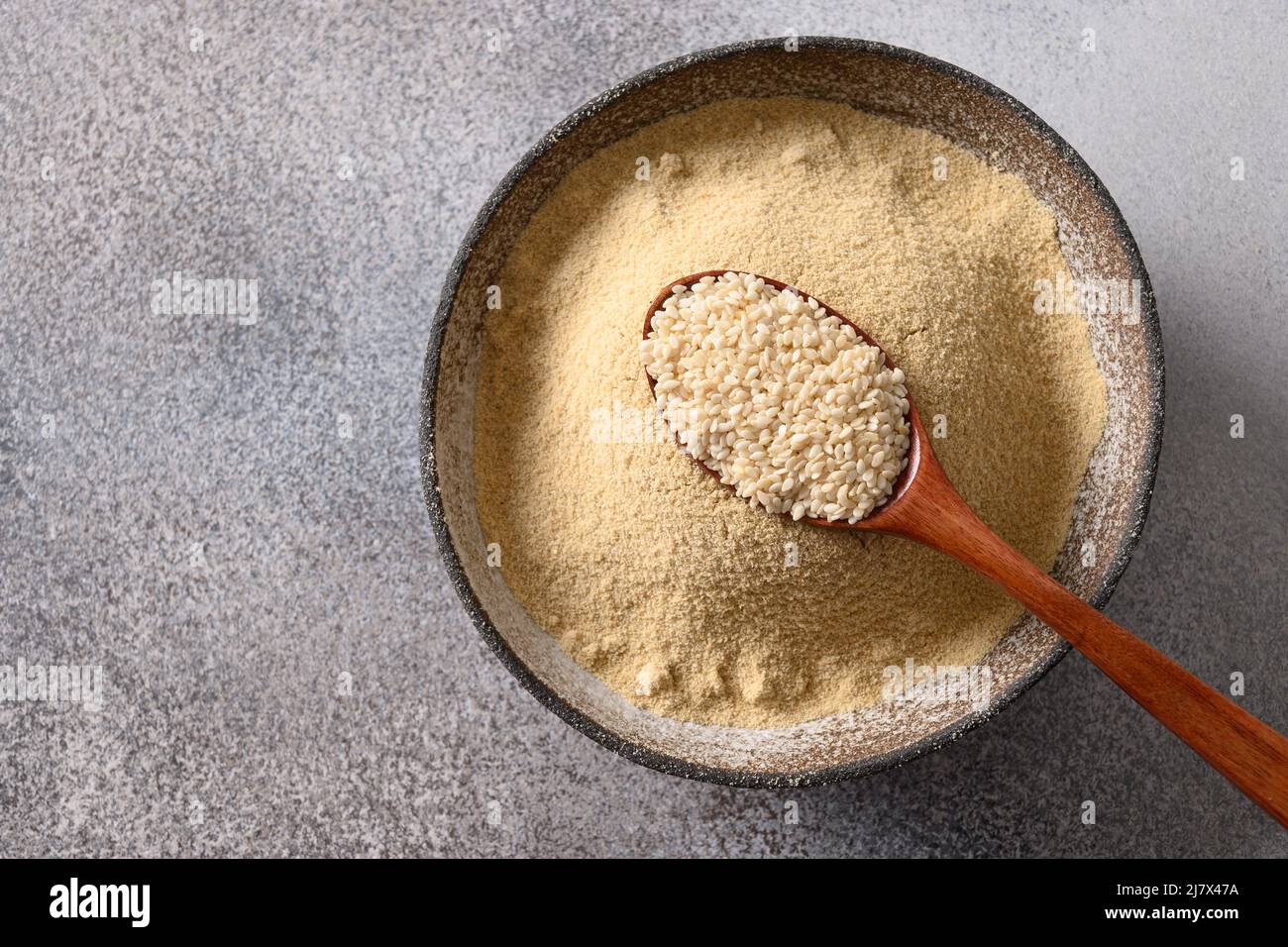 Sesame flour in bowl on gary background for cooking gluten-free and low carbohydrate dessert. Sesame flour includes ample minerals, natural antioxidan Stock Photo