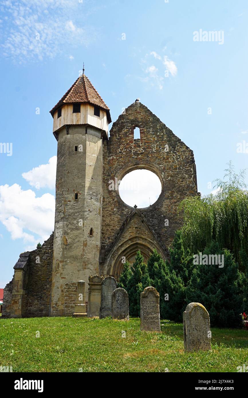 Grave stones in front of the Tower of Cârța Monastery, with blue sky and white clouds