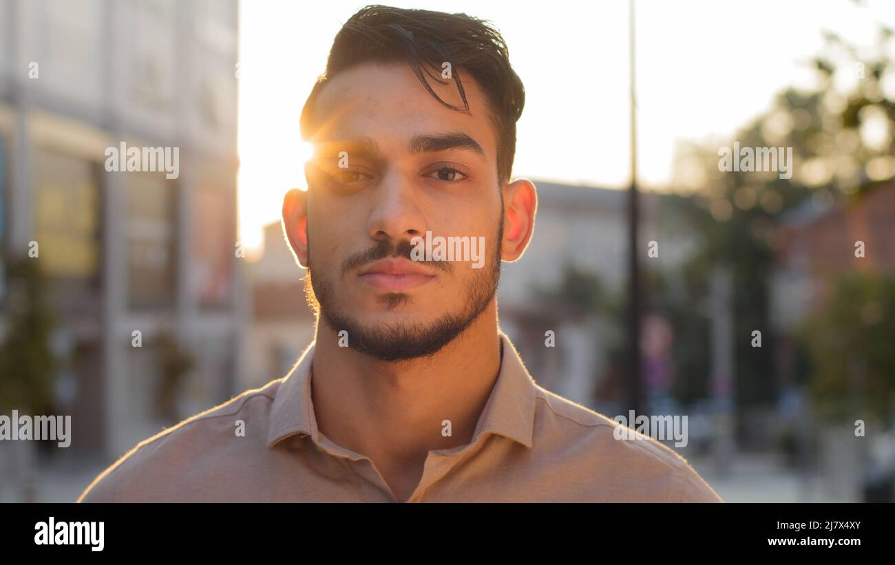 Portrait male calm serious face outdoors on street in city sunlight background. Hispanic arabic bearded guy business man successful entrepreneur Stock Photo