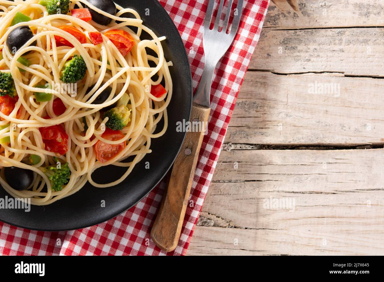 Spaghetti with vegetables(broccoli,tomatoes,peppers) on wooden table Stock Photo