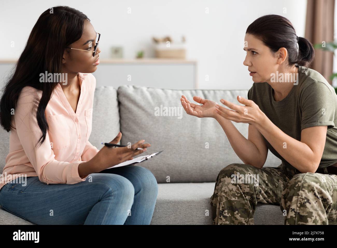 Worried Female Soldier Talking To Black Psychologist During Therapy