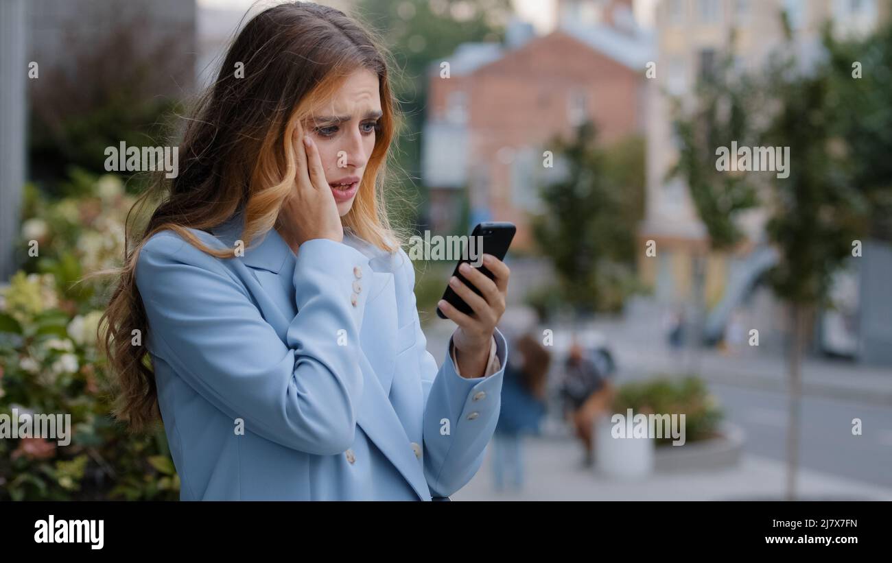 Business woman caucasian girl lady female looking in mobile phone feels shock upset worries about bad news problems of refusal financial notification Stock Photo