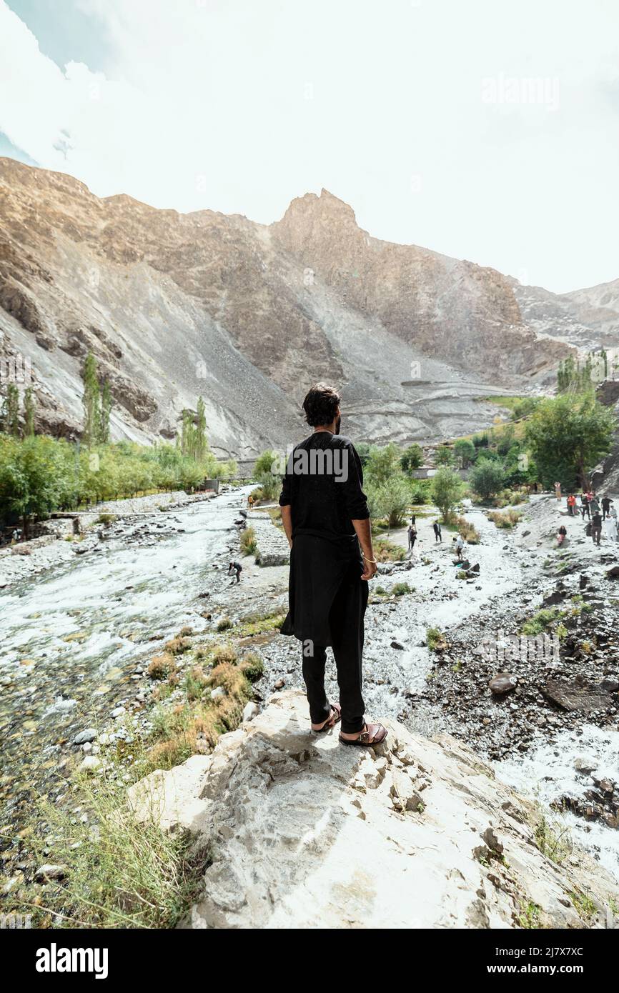 young adult man standing in a traditional black shalwar kameez at Manthokha Waterfall Stock Photo
