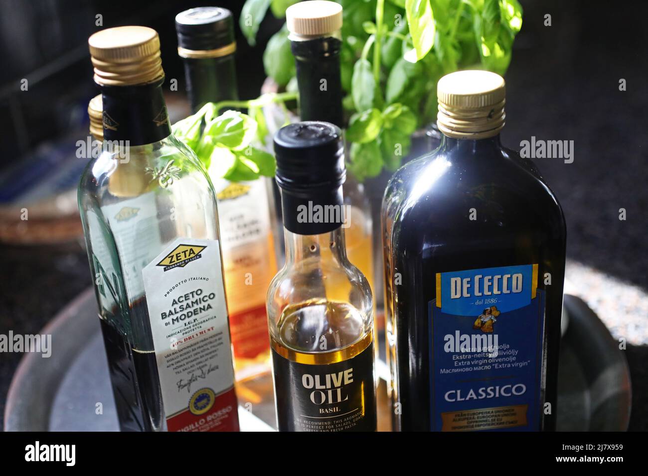 Different kinds of olive oil in a kitchen in a home. Here Aceto Balsamico from Zeta, basil olive oil and De Cecco olive oil. Stock Photo