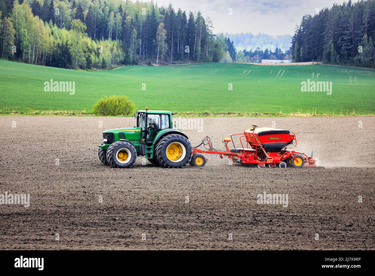 Farmer working with John Deere 6820 tractor and Väderstad Biodrill seed drill in field on a day of spring. Salo, Finland. May 15, 2021. Stock Photo