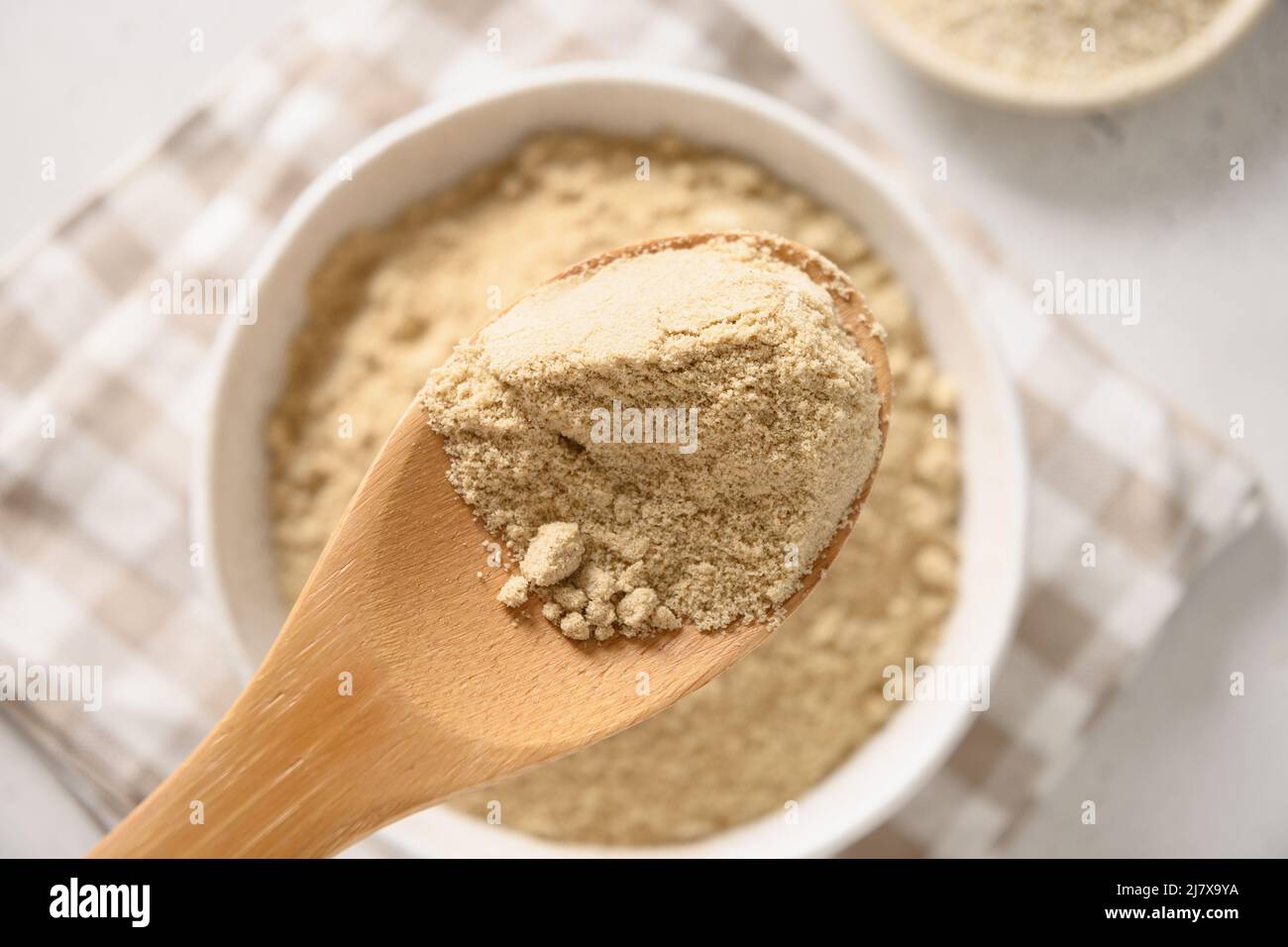 Sesame flour in wooden spoon. Close up. Good vegan source of protein, minerals, natural antioxidants and vitamins. Stock Photo