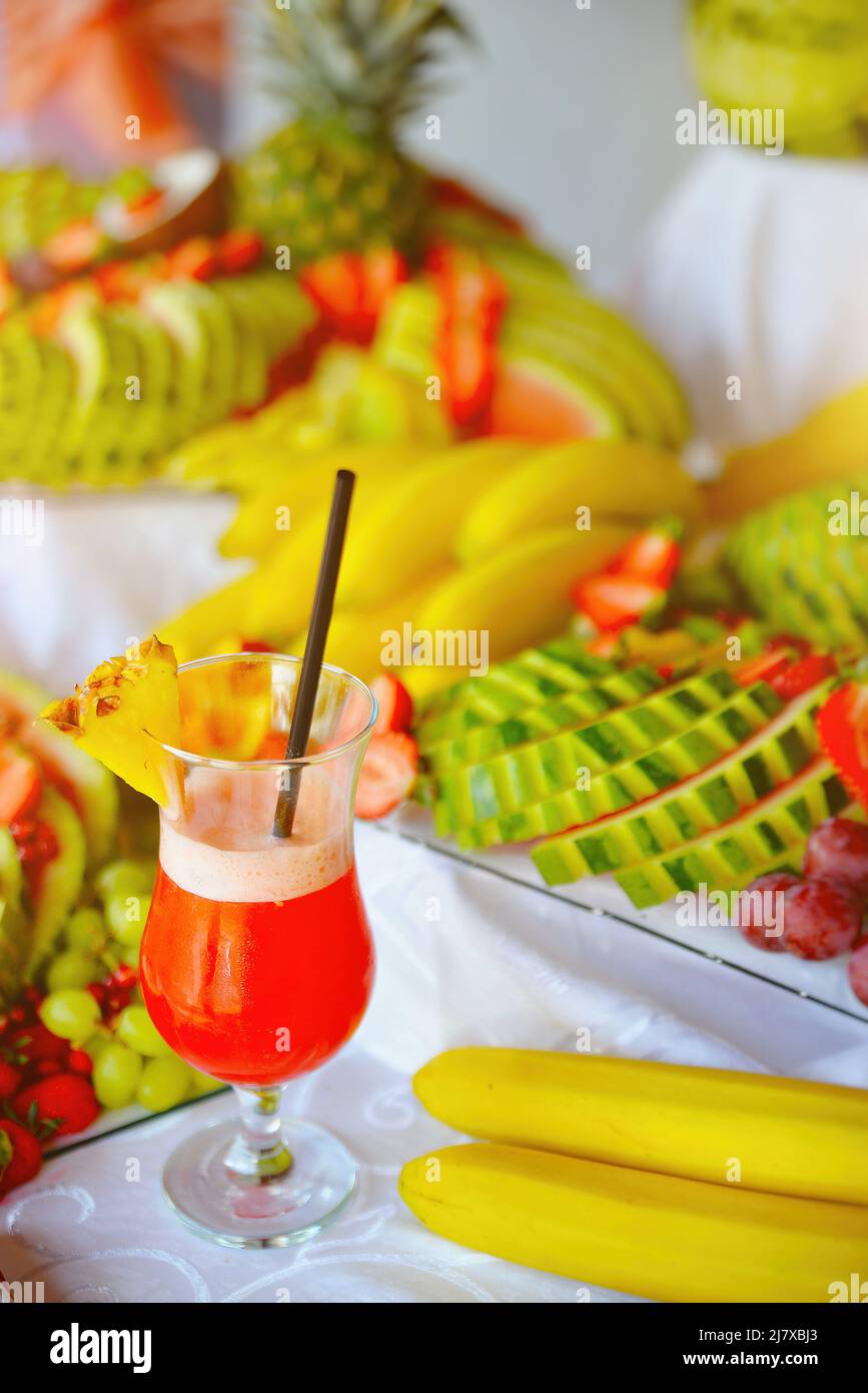 Fruit cocktail juice in glass with many tropical fruits in background Stock Photo