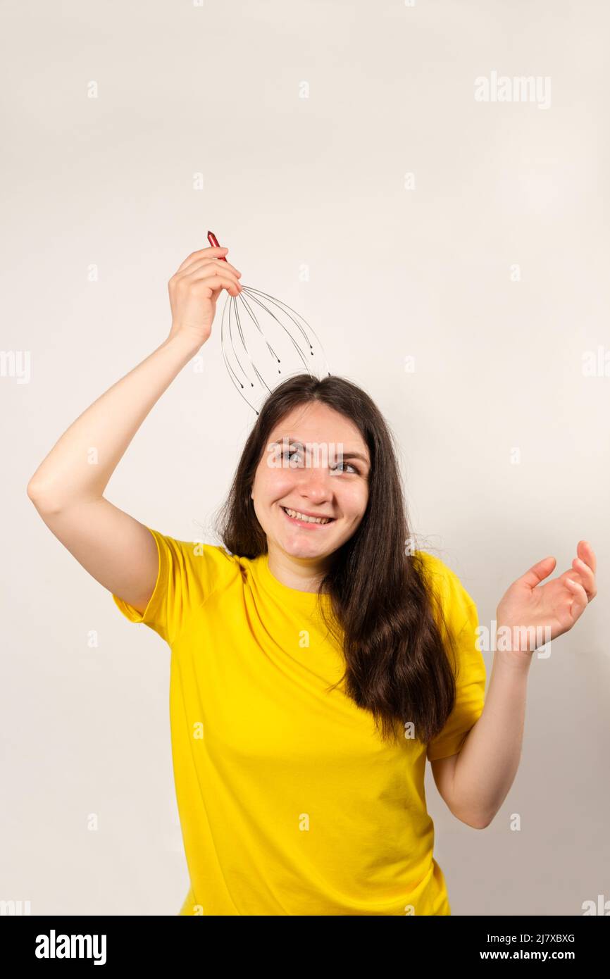 A woman with a metal flexible massager for self-massage of the head on a white background. Stock Photo