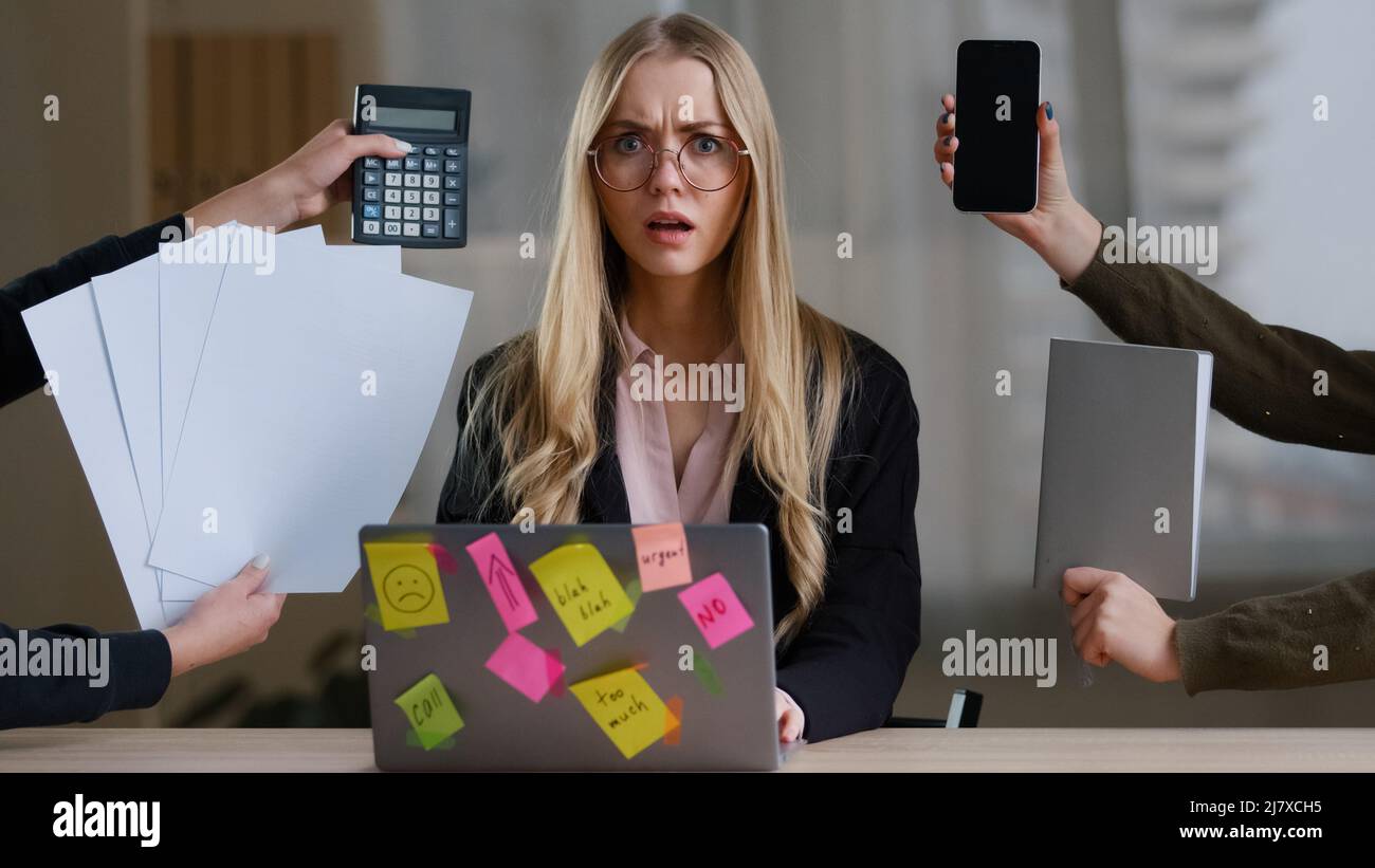 Multitasking business woman manager in office sitting at table have many tasks work feeling stress overworked exhausted from hands with calculator Stock Photo