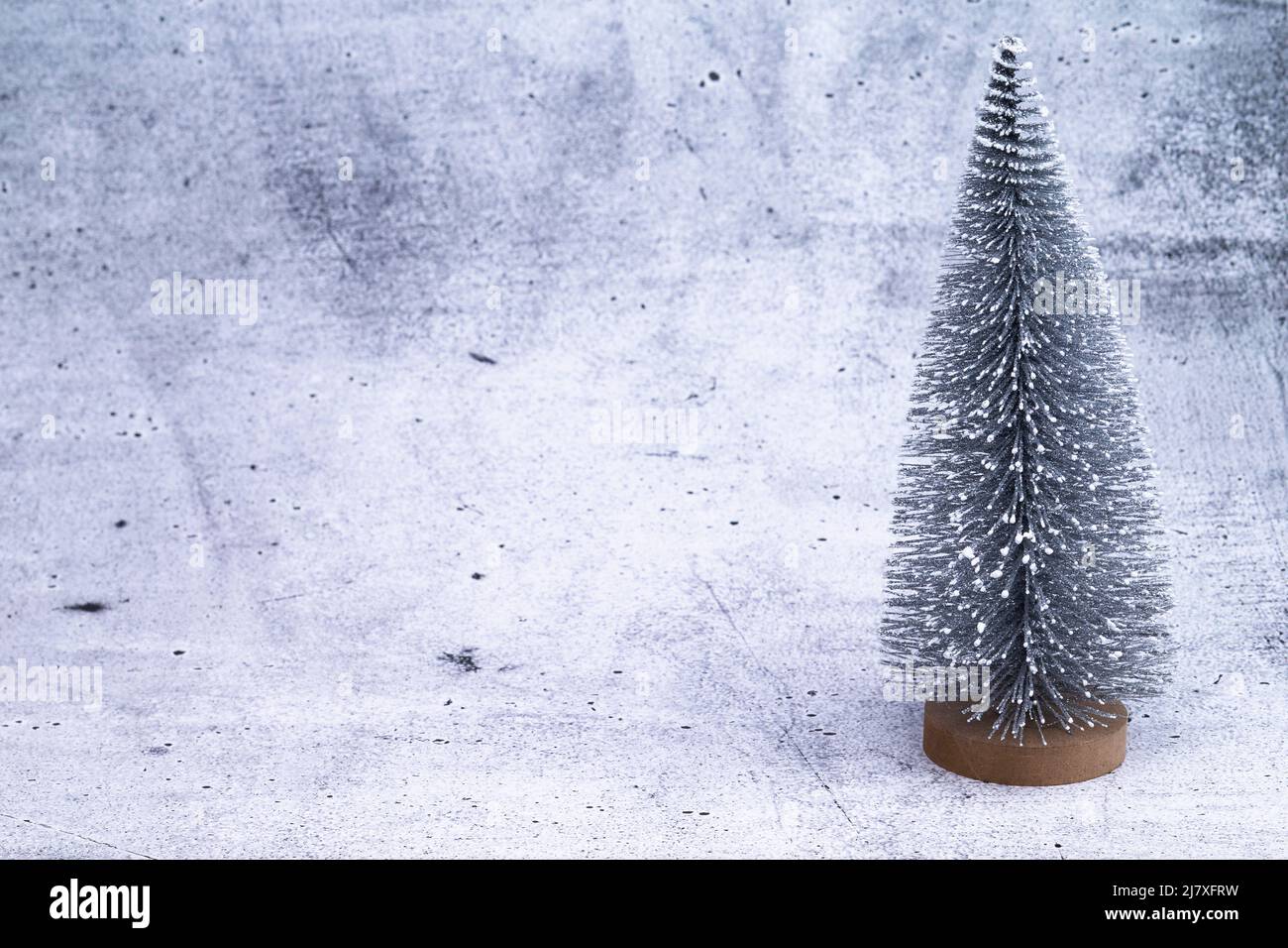 The photo shows a miniature Christmas tree on concrete background Stock Photo