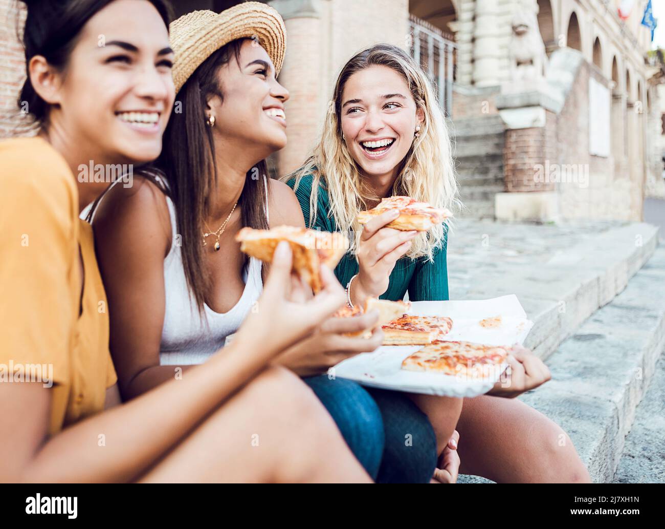 Happy young women tourists eating italian pizza enjoying summer vacation Stock Photo