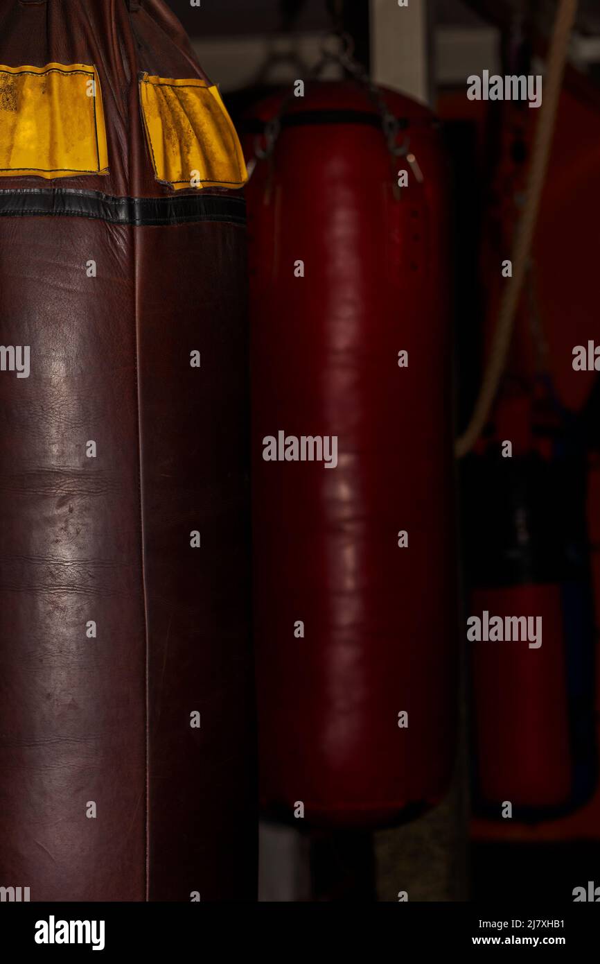 Old brown leather boxing bag hanging in the boxing gym, with red boxing