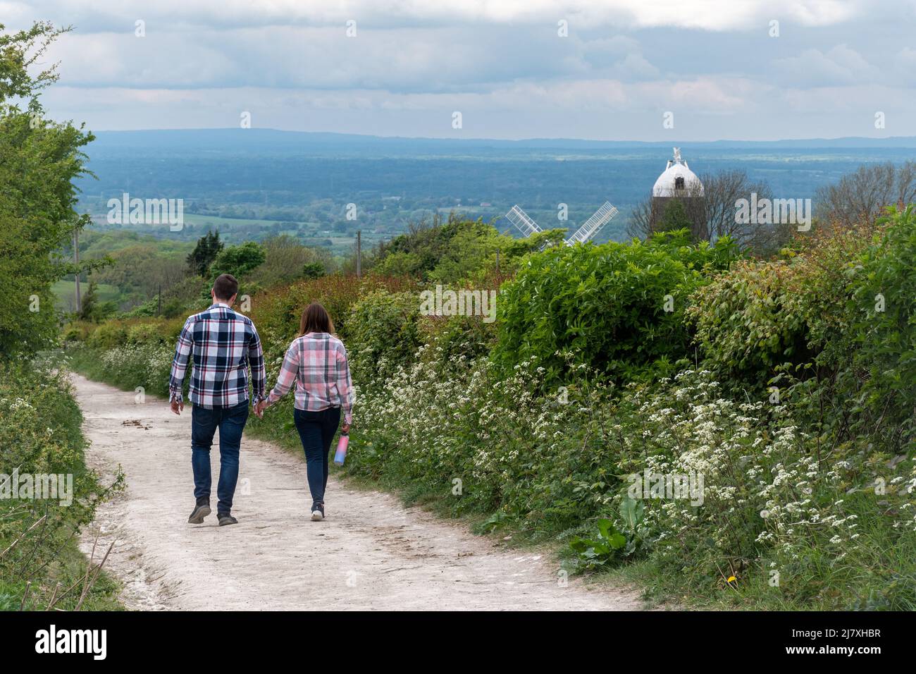 Couple walking on the South Downs Way path close to the Jack and Jill windmills, Clayton, West Sussex, England, UK Stock Photo