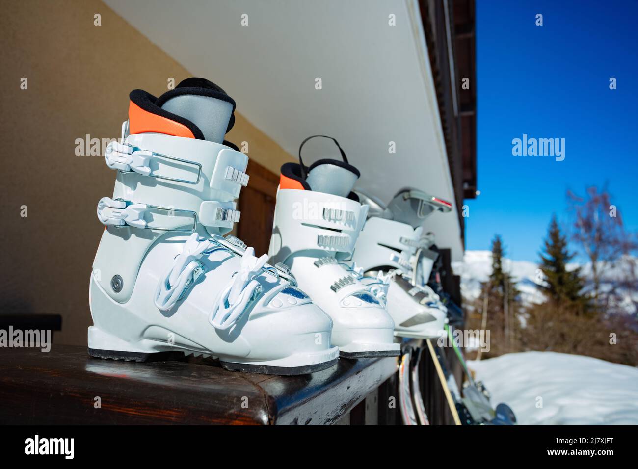 Row of many alpine ski boots on the balcony rail still Stock Photo