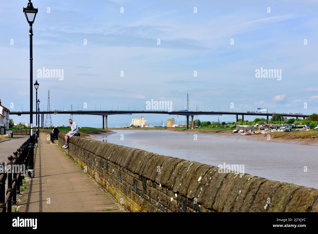 Tidal defensive wall along the estuary of River Avon at village of Pill, North Somerset, England. Avonmouth Bridge in background Stock Photo