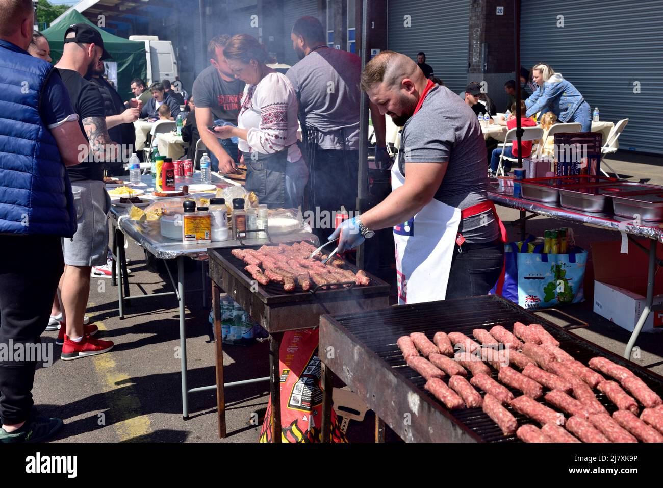 Stall at outdoor market stand with chef cooking and selling fresh barbecued sausages, Bristol Sunday market Stock Photo