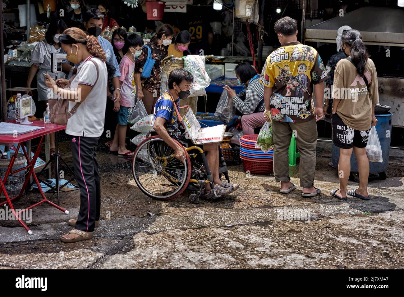 Disabled man working in a wheelchair selling lottery tickets at a Thailand street market Stock Photo