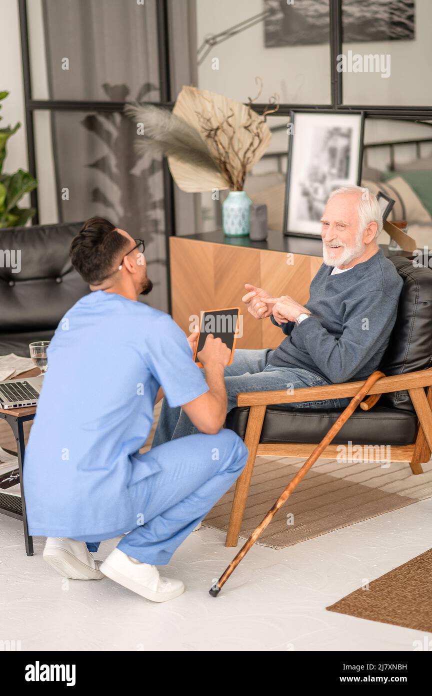 Elderly man listing things during the talk with his caretaker Stock Photo