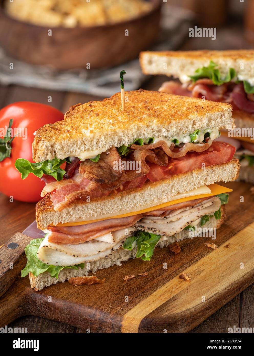 Club sandwich made with bacon, ham, turkey, cheese, lettuce and tomato