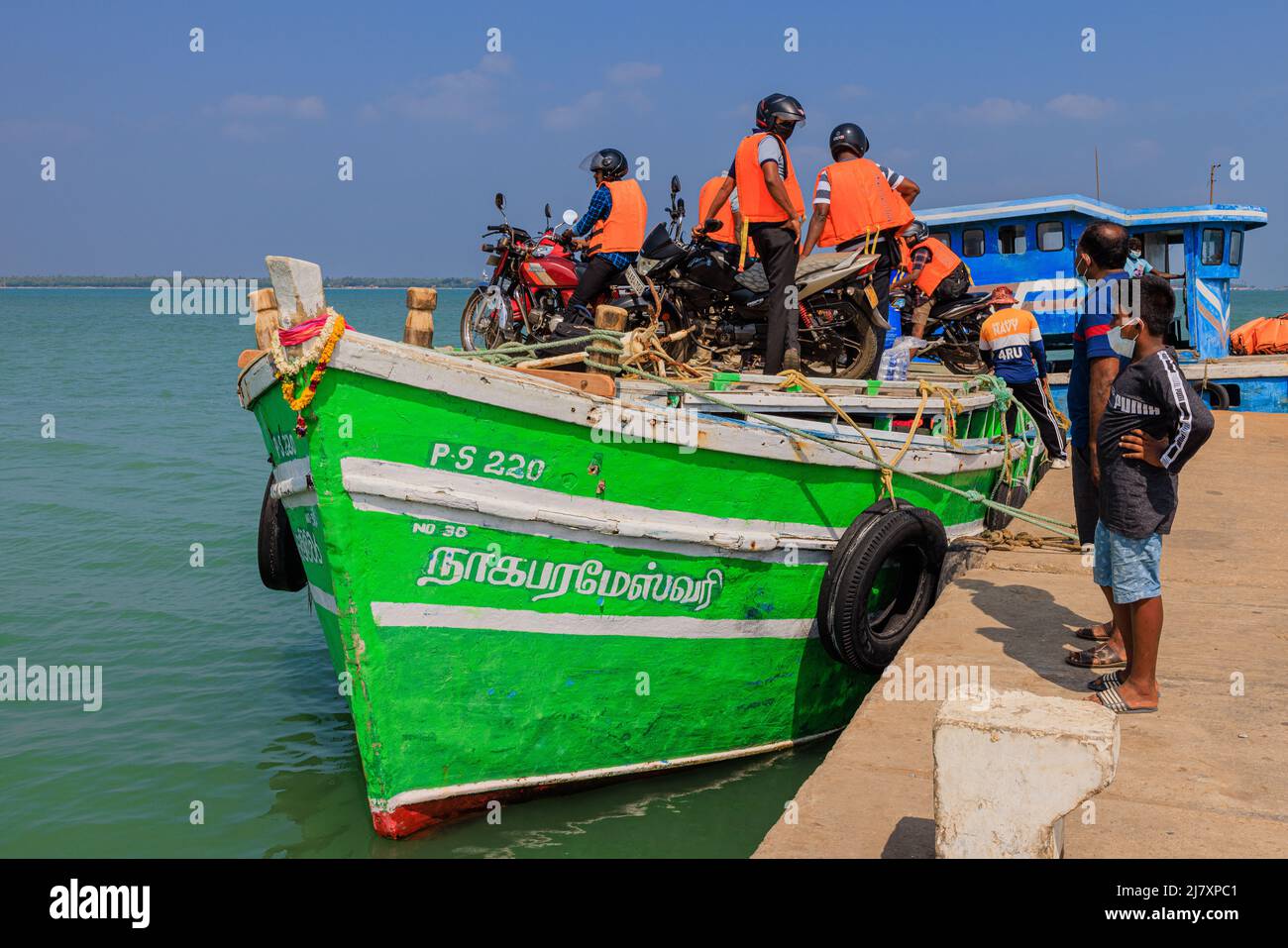 bikers in high viz hang on to their motor bikes on the roof of the ferry on a calm sea from punkudativu island jaffna peninsula sri lanka Stock Photo