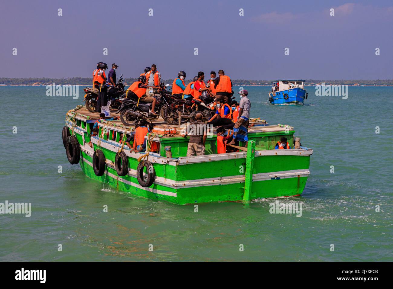 bikers in high viz hang on to their motor bikes on the roof of the ferry on a calm sea from punkudativu island jaffna peninsula sri lanka Stock Photo
