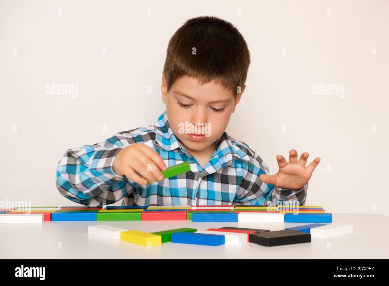 A preschooler boy plays with multicolored wooden blocks for
