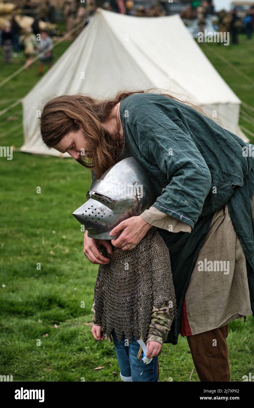 A viking warrior helps a boy try on a knight's helmet at the No Man's Land Event at Bodrhyddan Hall, Wales Stock Photo