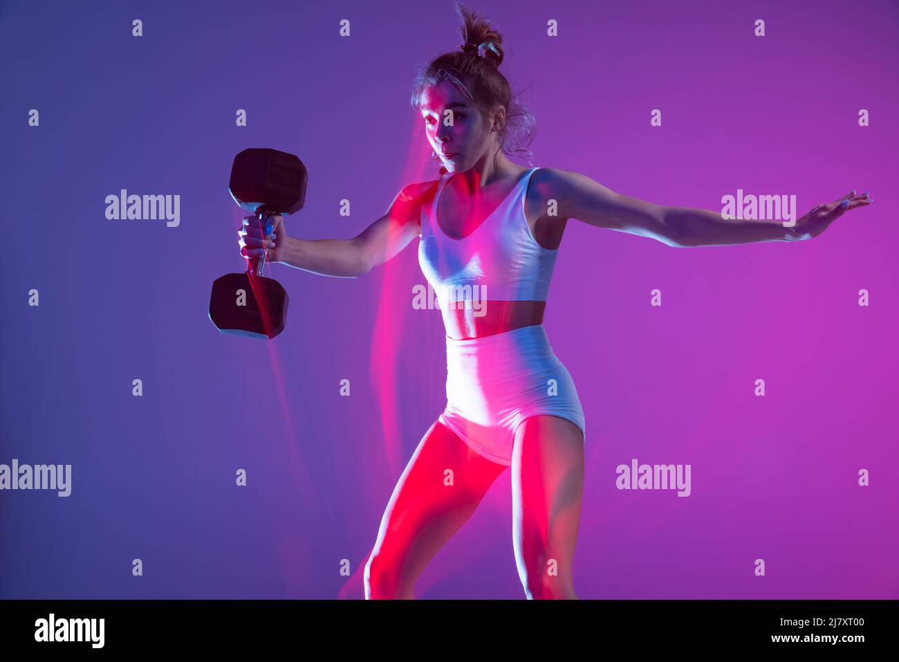 Workout. Young sportive girl training with weights isolated on gradient