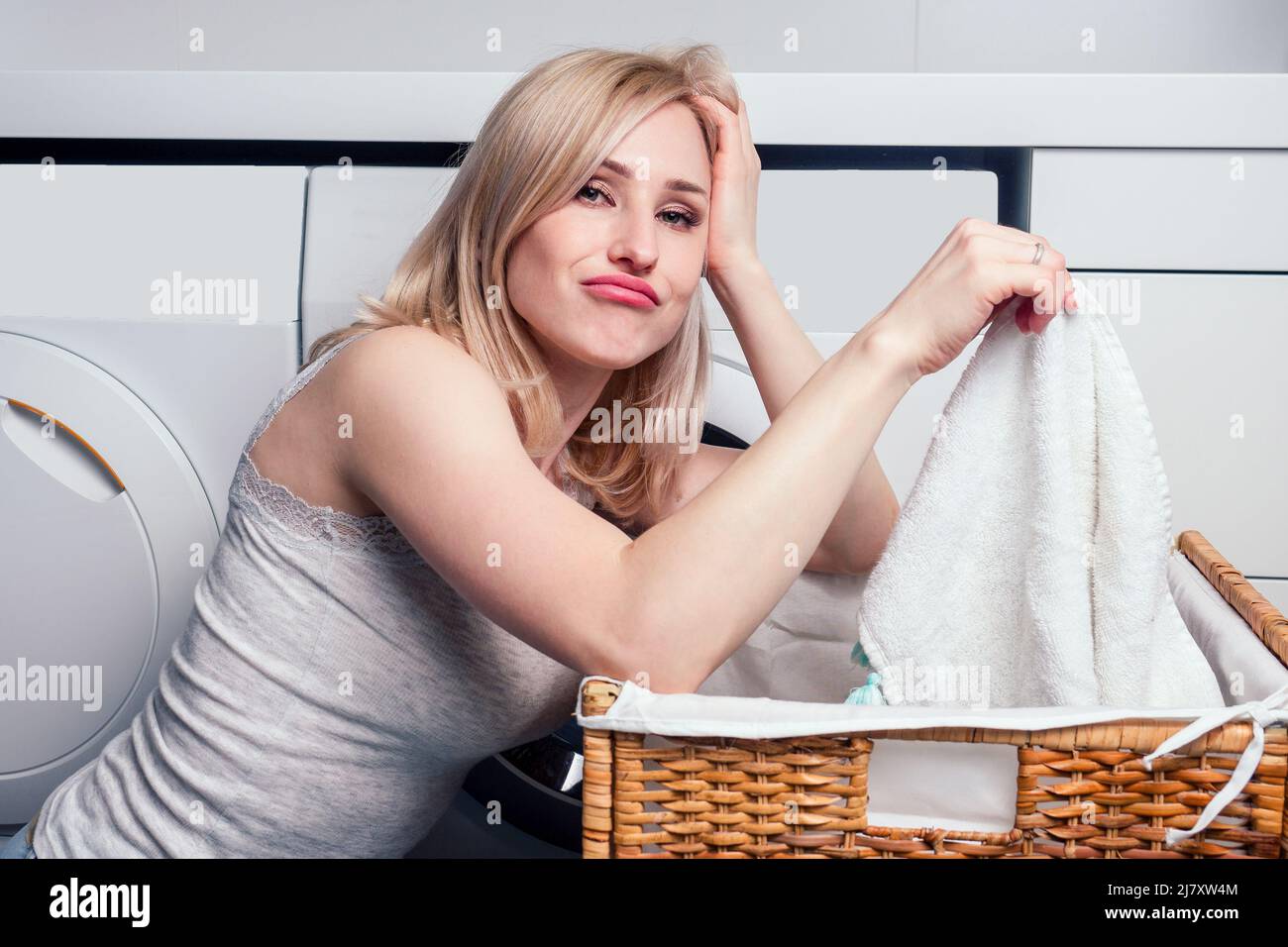 happy blonde female washing clothes feeling happy about soft fresh laundry aroma fabric softener aromatherapy Stock Photo