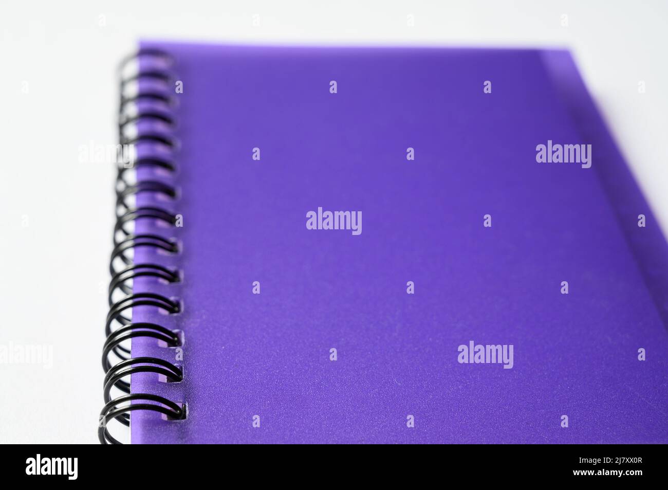 Perspective of wirebound (or spiral bound) notebook with purple, translucent plastic cover on white background. Stock Photo