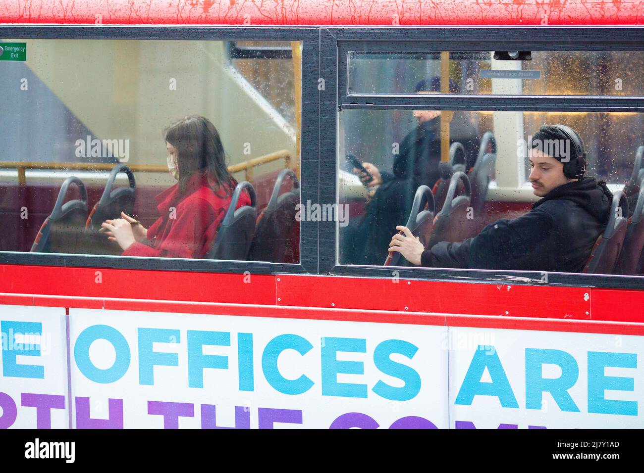 Passengers, some wearing a mask and others not, are seen in a double-decker bus in the City of London. Stock Photo
