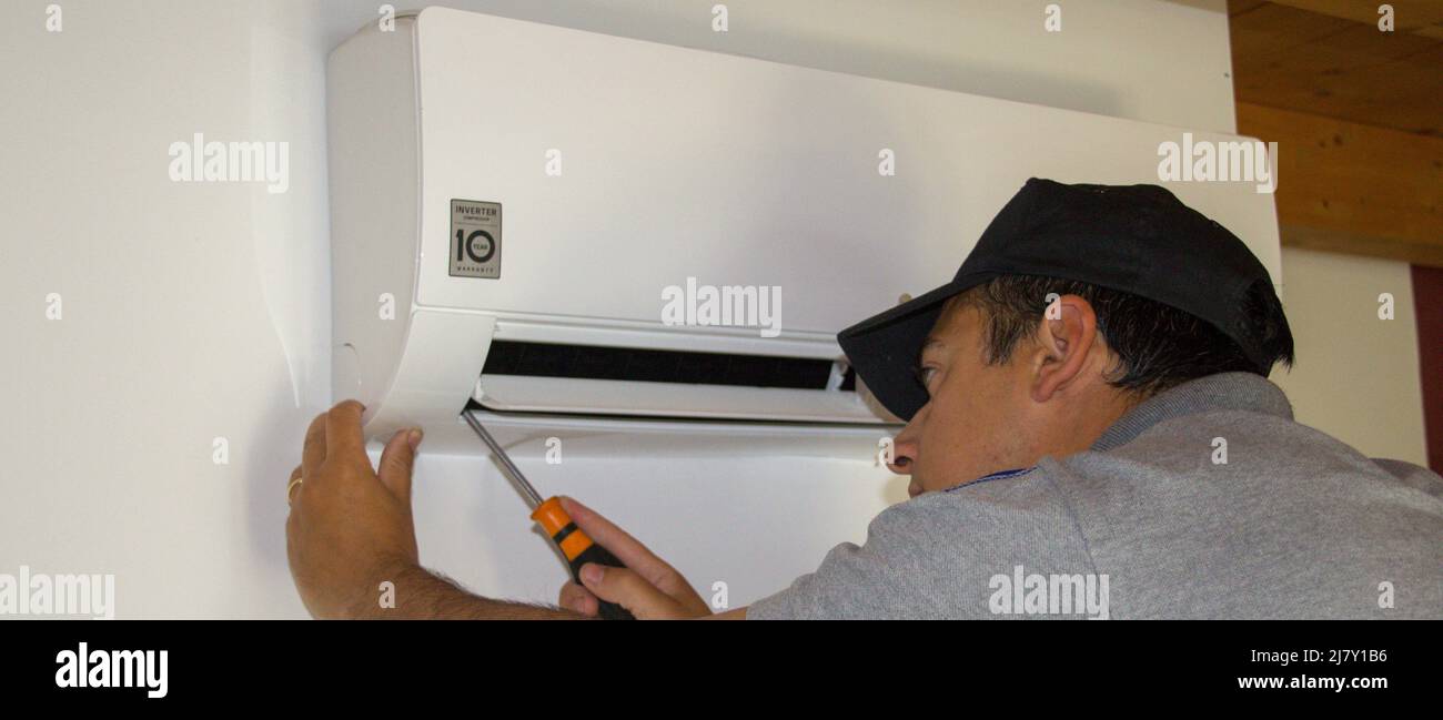 Plumber on a ladder who, with a screwdriver in hand, carries out