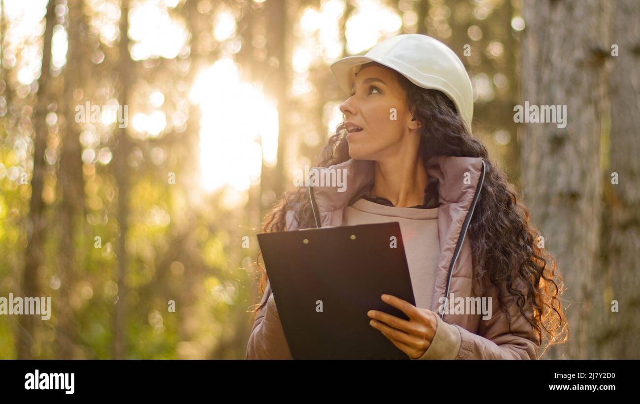 Female technician with clipboard taking measures for reforestation of woodlands. Forest evaluation and management. Millennial indian Forestry engineer Stock Photo