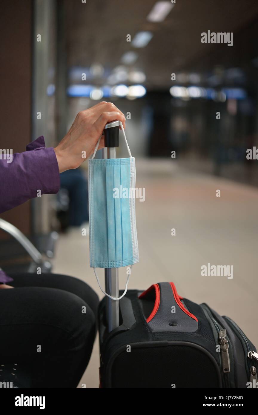 Travel Restrictions. Woman Waiting With Face Mask and Luggage in Airport Stock Photo