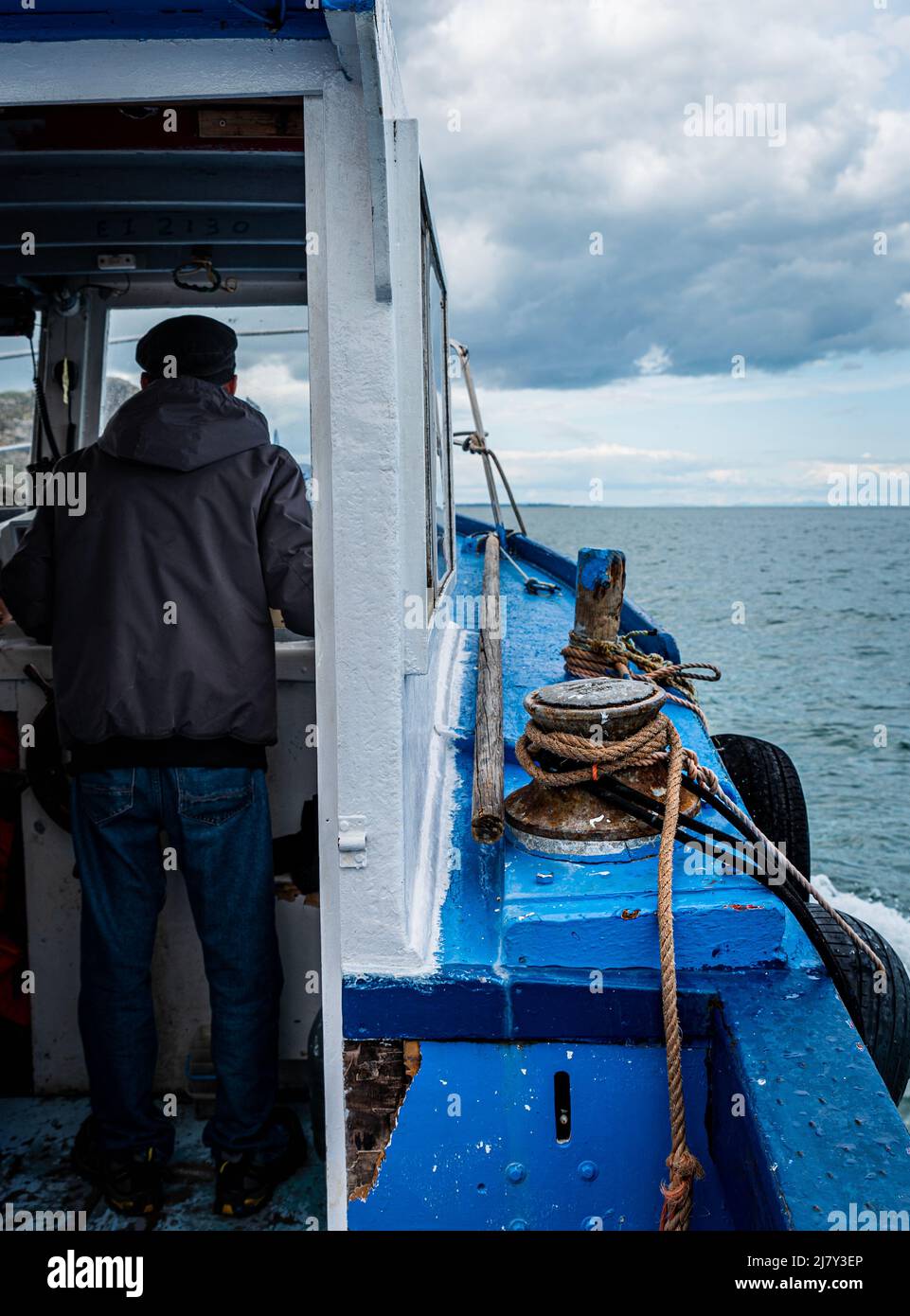 Fishing boat, view of both cabin and sea, being sailed by an old ...
