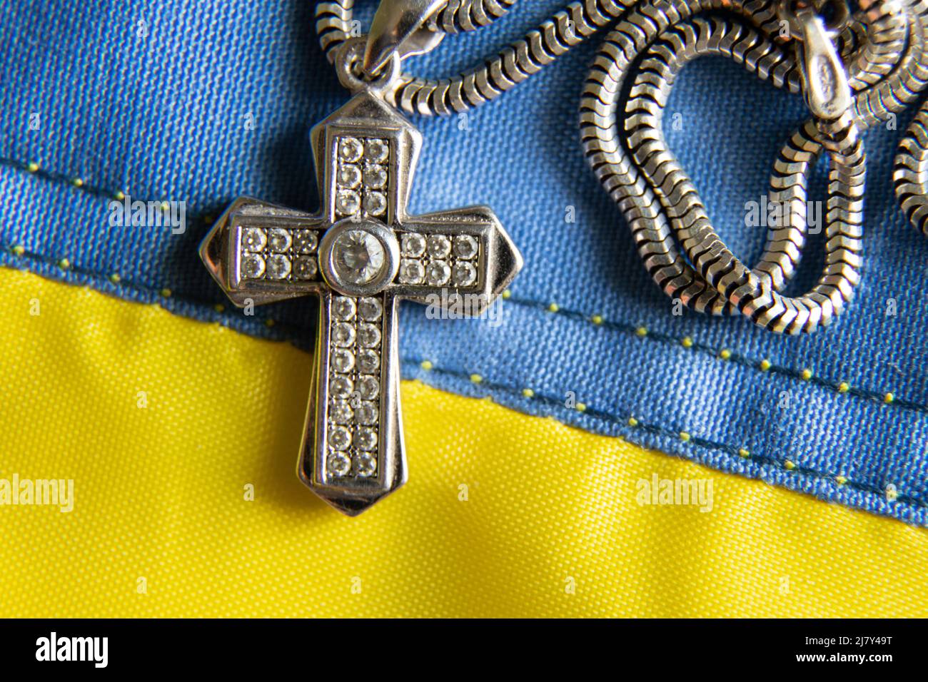 The flag of Ukraine is yellow-blue and a silver cross as a background, a prayer for Ukraine during a full-scale war, faith and religion Stock Photo