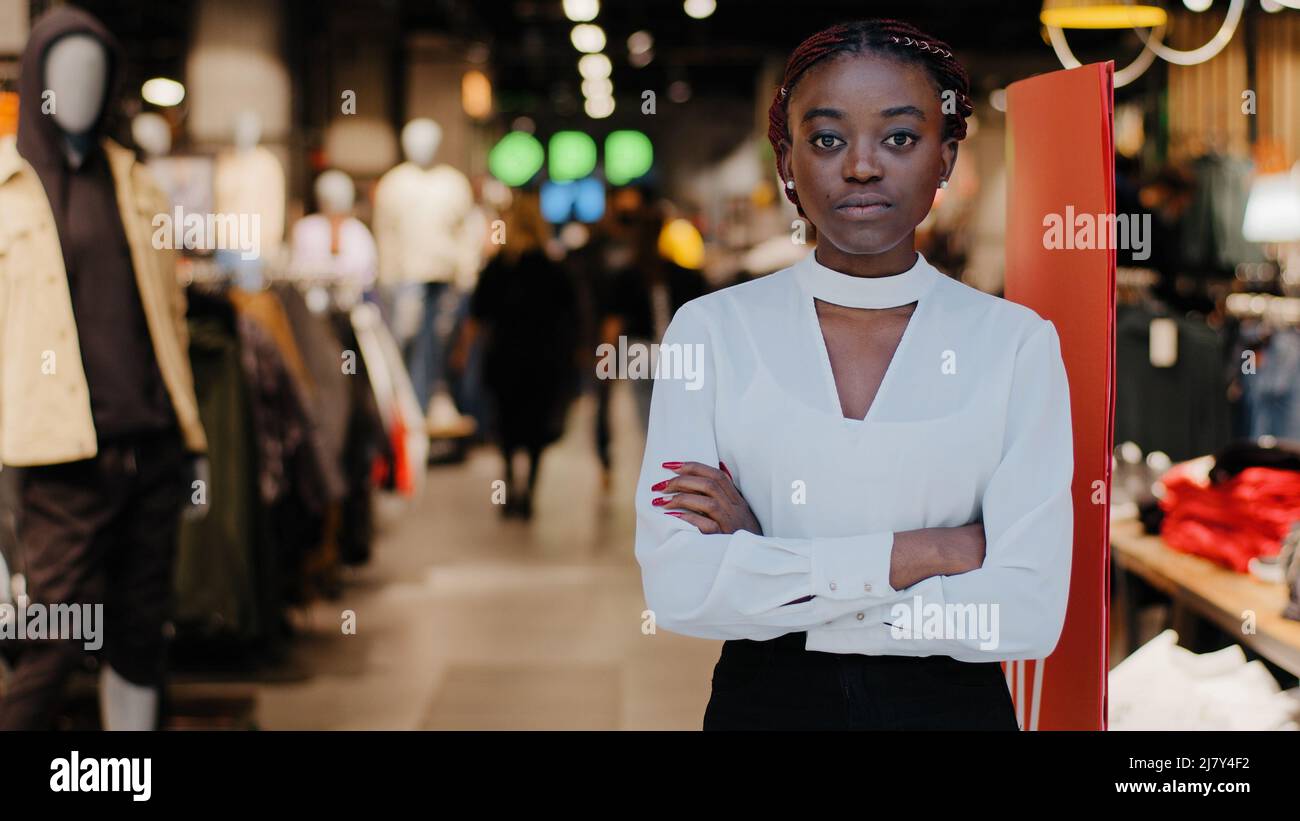 Successful lady small business woman african american girl female salesman clothing store owner stands at entrance to shopping center looking at Stock Photo