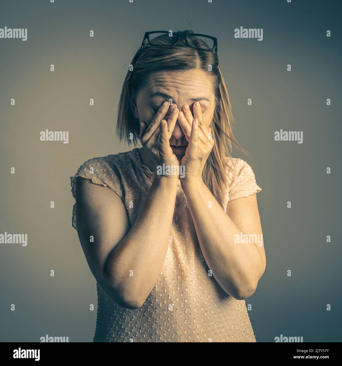 tired woman rubs her eyes with her hands Stock Photo