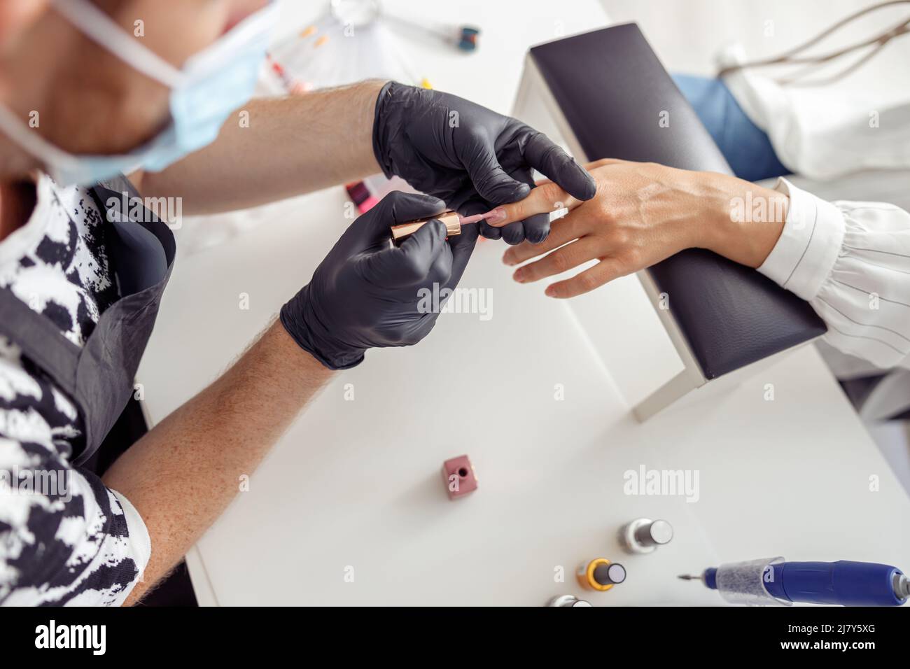 Creative nail master processing nails of his client in salon Stock