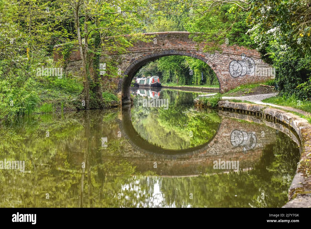 An old bridge reflected in the perfectly still waters of the Grand Union Canal in Milton Keynes Stock Photo