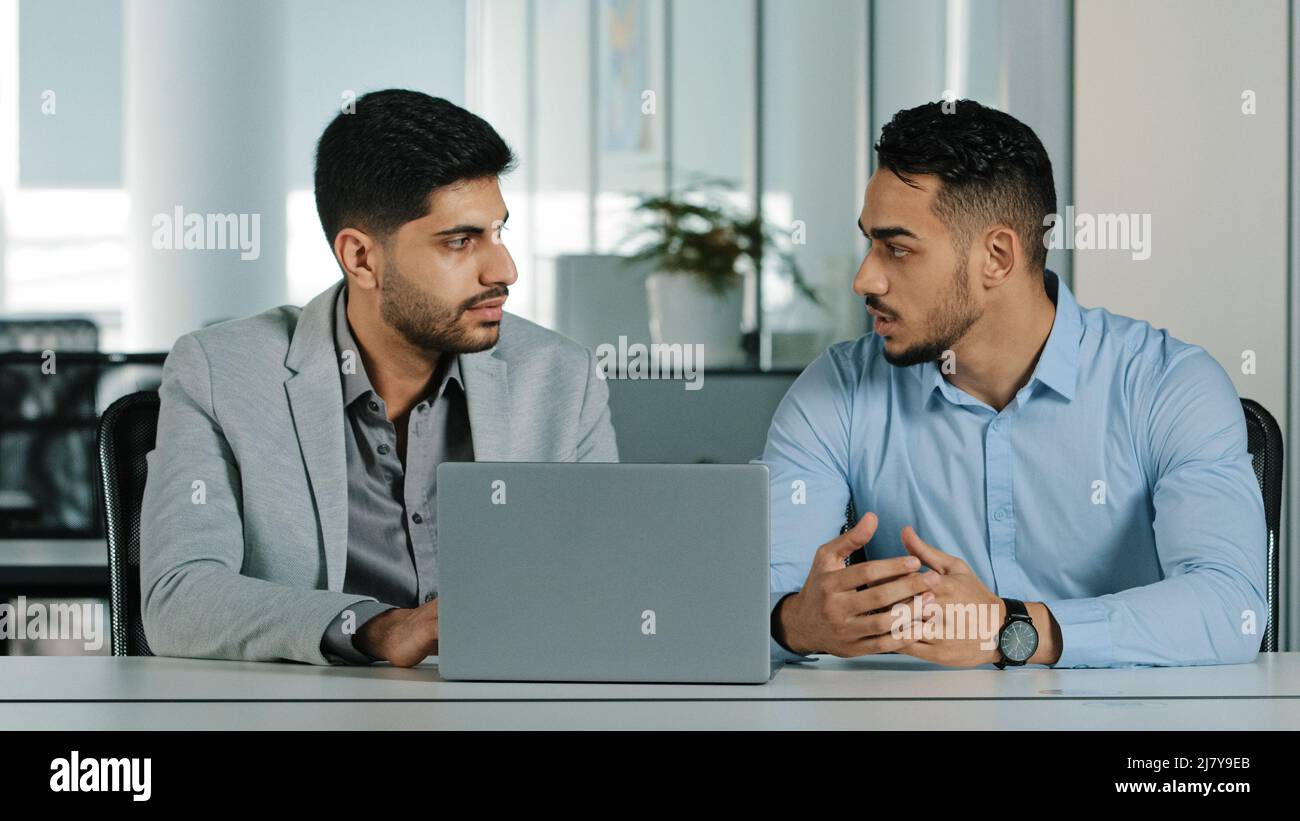 Confident arabic male financial consultant adviser expert talking to indian client customer explain commercial investment deal benefit show computer Stock Photo