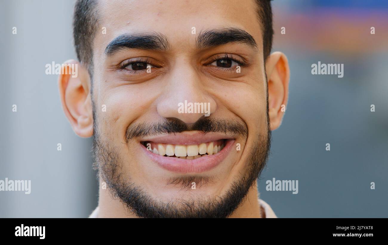 Close up outdoors head male portrait young hispanic happy smiling handsome business man standing in city. Healthy bearded guy arabic client with Stock Photo